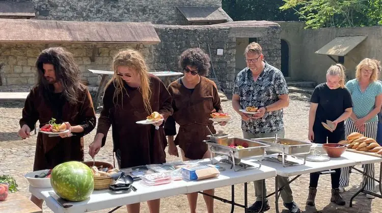Gasten halen eten van een buffet buiten, bediend door medewerkers in Romeinse gewaden