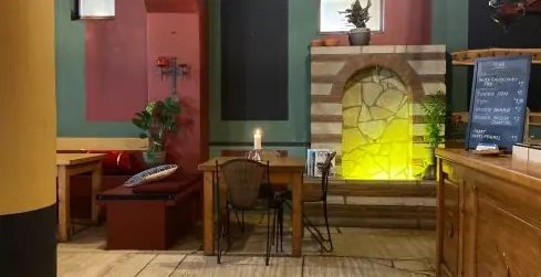 Tafels naast een stenen boog met verlichte nis en een krijtbord