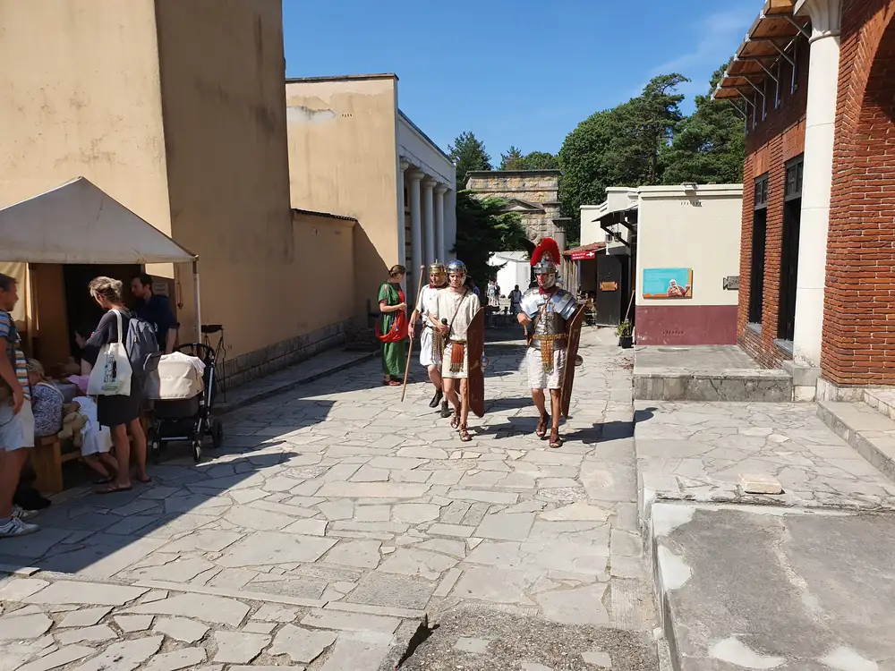 Een stenen straat in het Romeinse dorp van het park, met wandelaars en soldaten in Romeinse uitrusting