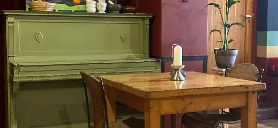 Een groene piano naast een houten tafel met een kaars