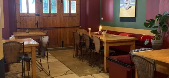 Houten tafels onder een groen en bordeauxrood gekleurde muur met een lamp en plant